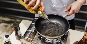 Cuisinier qui verse de l'huile dans une poêle